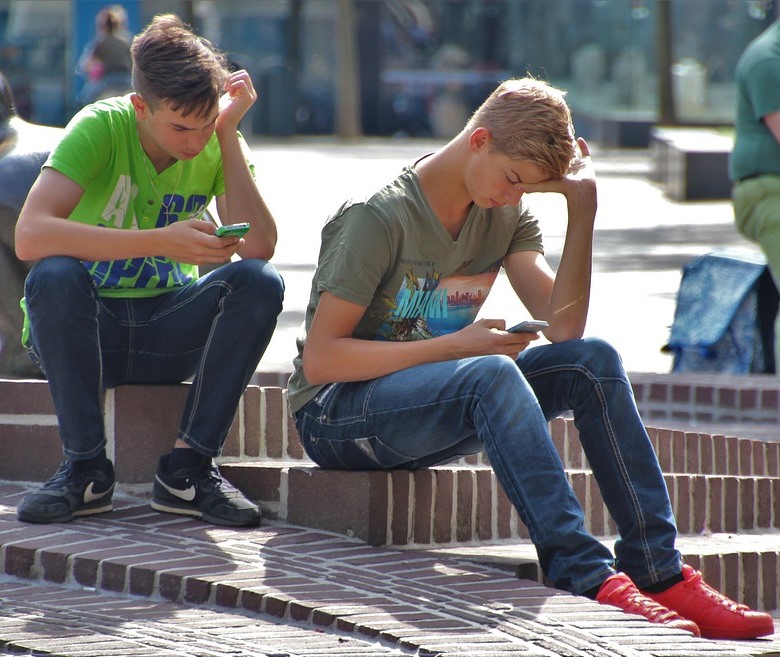 Jóvenes miran su teléfono móvil en la calle