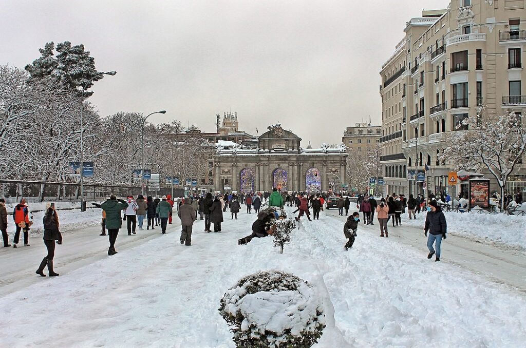 Un grupo de personas caminando en la nieve cerca de la Puerta de Alcala en Madrid